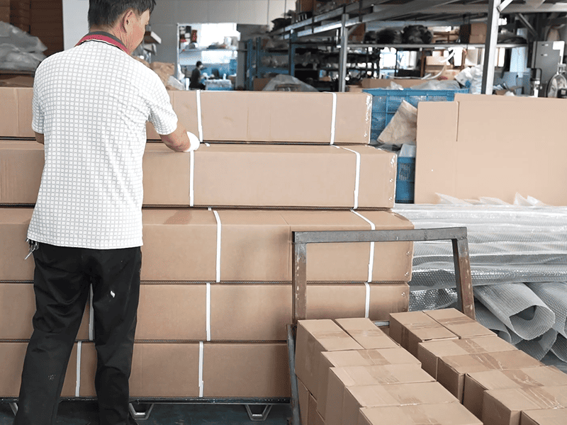 Worker securing cartons of automotive parts in a factory packing area