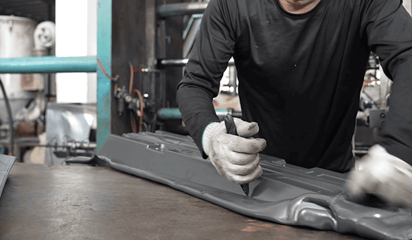 Worker marking an automotive exterior component during project preparation