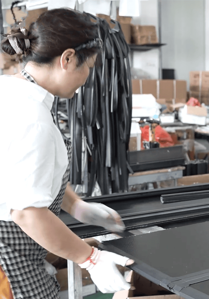Worker handling black automotive exterior components in the factory