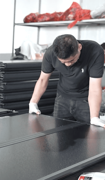 Worker reviewing the surface of a black automotive exterior panel