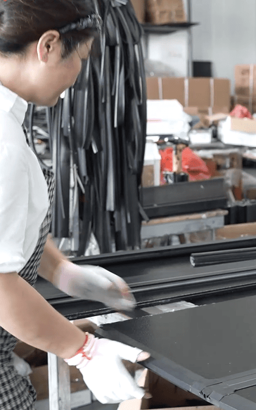 Worker inspecting a black automotive exterior component during production