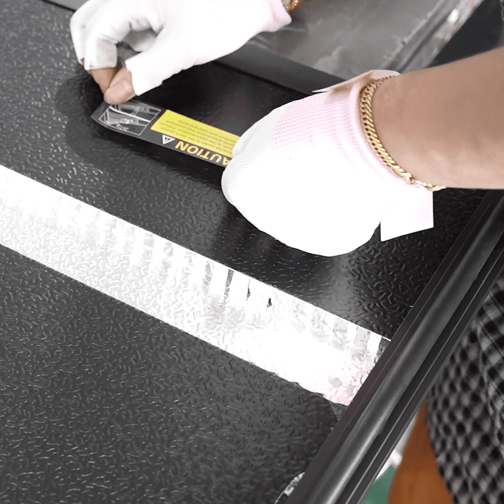 Worker assembling a black automotive exterior component in the factory