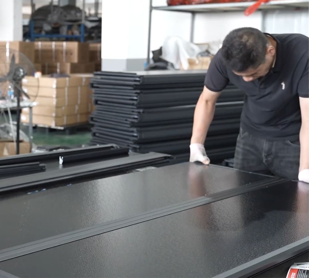 Factory worker inspecting a black automotive exterior component during production