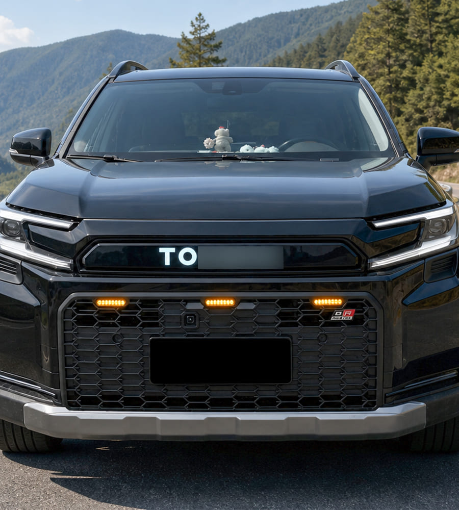 Front view of a black SUV with a large honeycomb grille and auxiliary lights