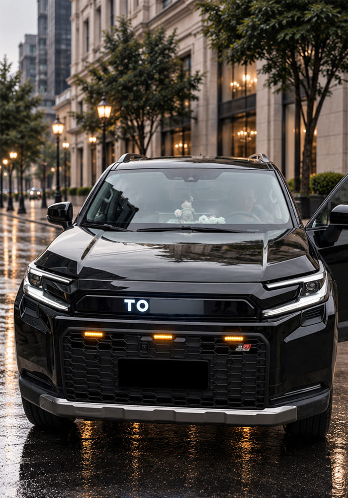 Front view of a black SUV showing the installed grille in wet street lighting
