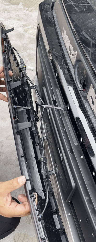 Technician connecting a front grille to the vehicle wiring and mounting area