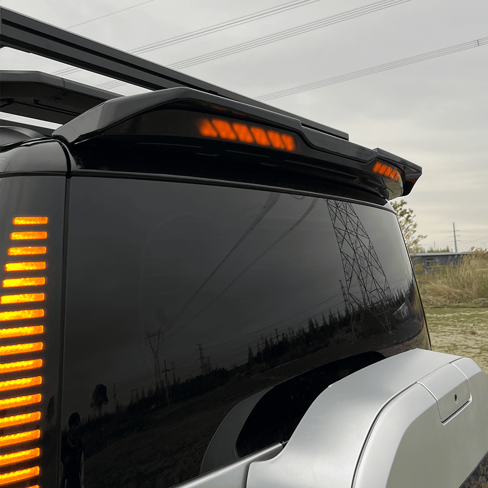Close rear view of a black SUV showing the illuminated roof spoiler and rear body profile