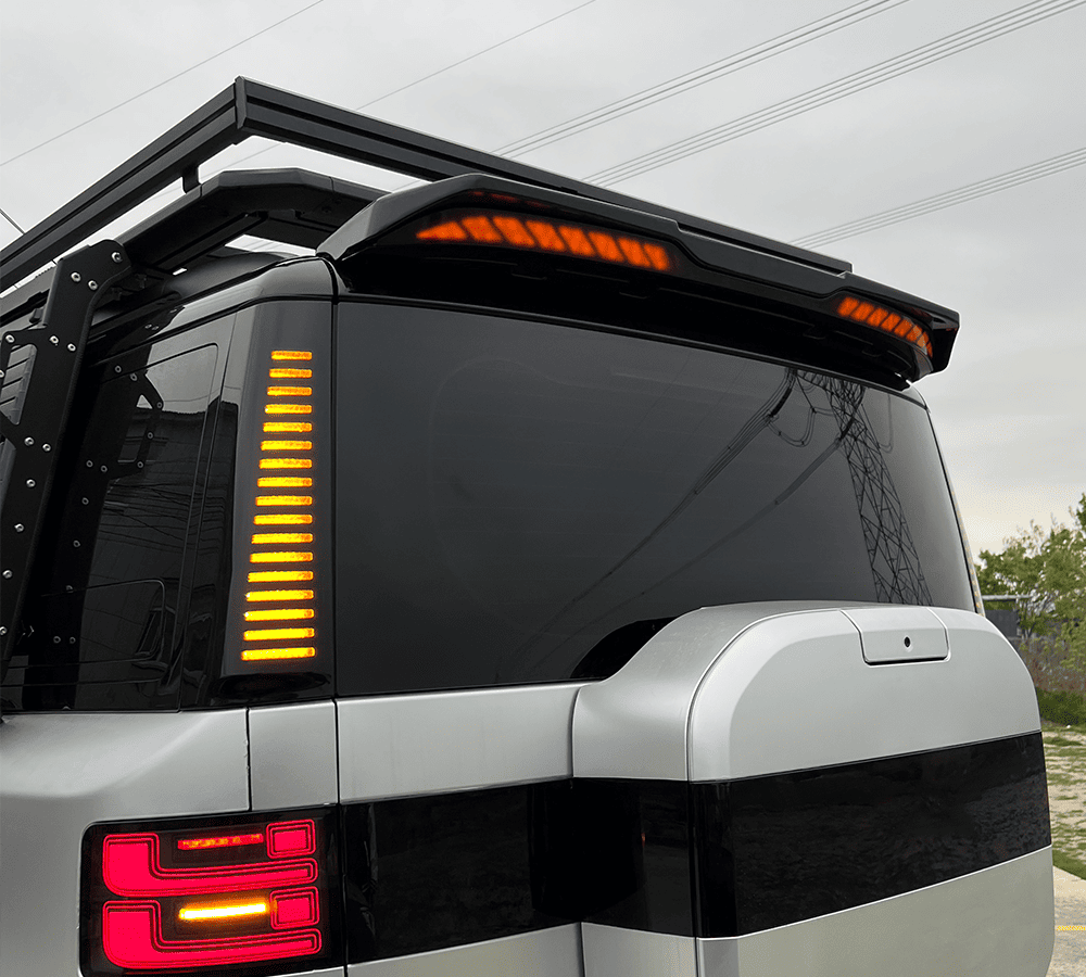 Rear vehicle spoiler with integrated amber lights on a white SUV
